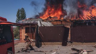 Firefighters try to put out a fire after the Russian shelling of a house in Bakhmut in Donetsk, Ukraine, on July 27, 2022.