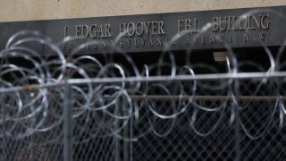 The sign for the J. Edgar Hoover FBI building can be seen through fencing and barbed wire surrounding construction on the side of the building in Washington, D.C., U.S., August 17, 2022.
