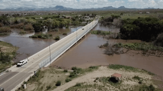 People drive over a bridge in Duncan, Ariz., following a flooding.