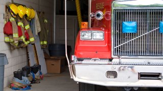 A fire truck is parked in the bay with all of the fire fighting equipment and gear ready to go.