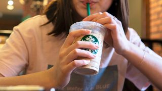 A girl drinks ice coffee in a Starbucks coffee shop in Tianjin, China.