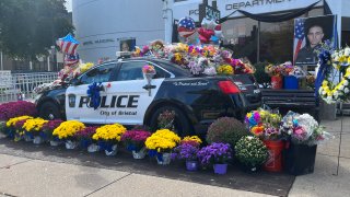 Dozens of flowers are placed on and around a Bristol police car in honor of fallen officers Dustin DeMonte and Alex Hamzy.
