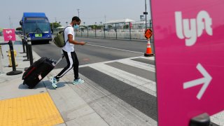 A traveler arriving at Los Angeles International Airport looks for ground transportation during a statewide day of action to demand that ride-hailing companies Uber and Lyft follow California law and grant drivers “basic employee rights” in Los Angeles, California, U.S., August 20, 2020.