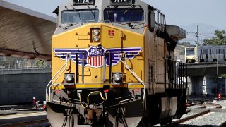 A GE AC4400CW diesel-electric locomotive in Union Pacific livery, is seen ahead of a possible strike if there is no deal with the rail worker unions, as a Metrolink commuter train (right) arrives at Union Station in Los Angeles, California, September 15, 2022.