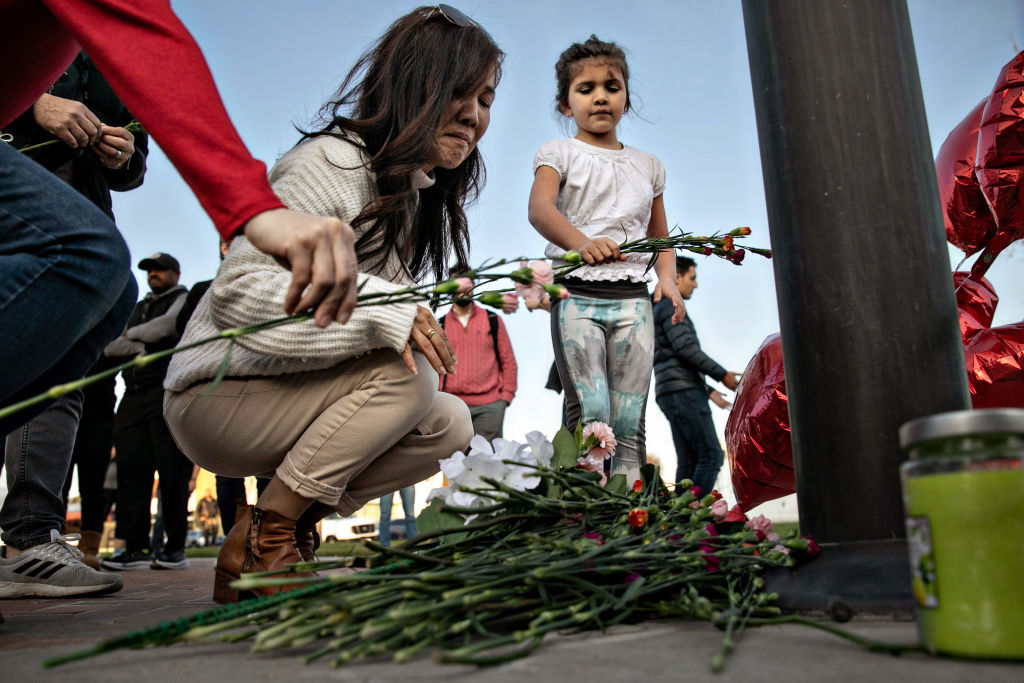 Mourners place flowers at a memorial where community members gathered for vigil to the people who were killed by a gunman who opened fire at a ballroom dance studio on Sunday, Jan. 22, 2023 in Monterey Park, California.