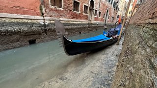 A gondola is docked on a dry canal during a low tide in Venice, Italy, Monday, Feb. 20, 2023. Some of Venice’s secondary canals have practically dried up lately due a prolonged spell of low tides linked to a lingering high-pressure weather system.