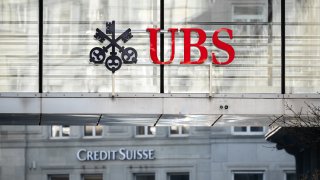 A sign and logo of Credit Suisse bank is seen beneath a sign of Swiss giant banking UBS in Zurich on March 20, 2023.