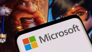 Microsoft logo is seen on a smartphone placed on displayed Activision Blizzard’s games character.