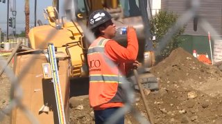 A construction worker takes a swig of water amid sweltering conditions in the Inland Empire.