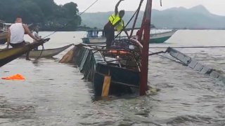 In this image from video provided by the Philippine Coast Guard, a man stands on a capsized passenger boat as they undergo rescue operations at Binangonan, Rizal province, east of Manila, Philippines on Thursday July 27, 2023.