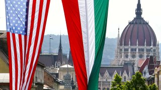 FILE – American and Hungarian national flags fly in downtown Budapest, Hungary, on Wednesday, June 21, 2006, with the historical parliament building at the background. The United States is imposing travel restrictions on citizens of Hungary over concerns that the identities of nearly 1 million foreigners granted Hungarian passports over nine years were not sufficiently verified. That’s according to the U.S. Embassy and a government official.