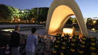 People visit and say prayers at sunrise at the cenotaph for the atomic bomb victims at the Peace Memorial Park in Hiroshima on August 6, 2023.