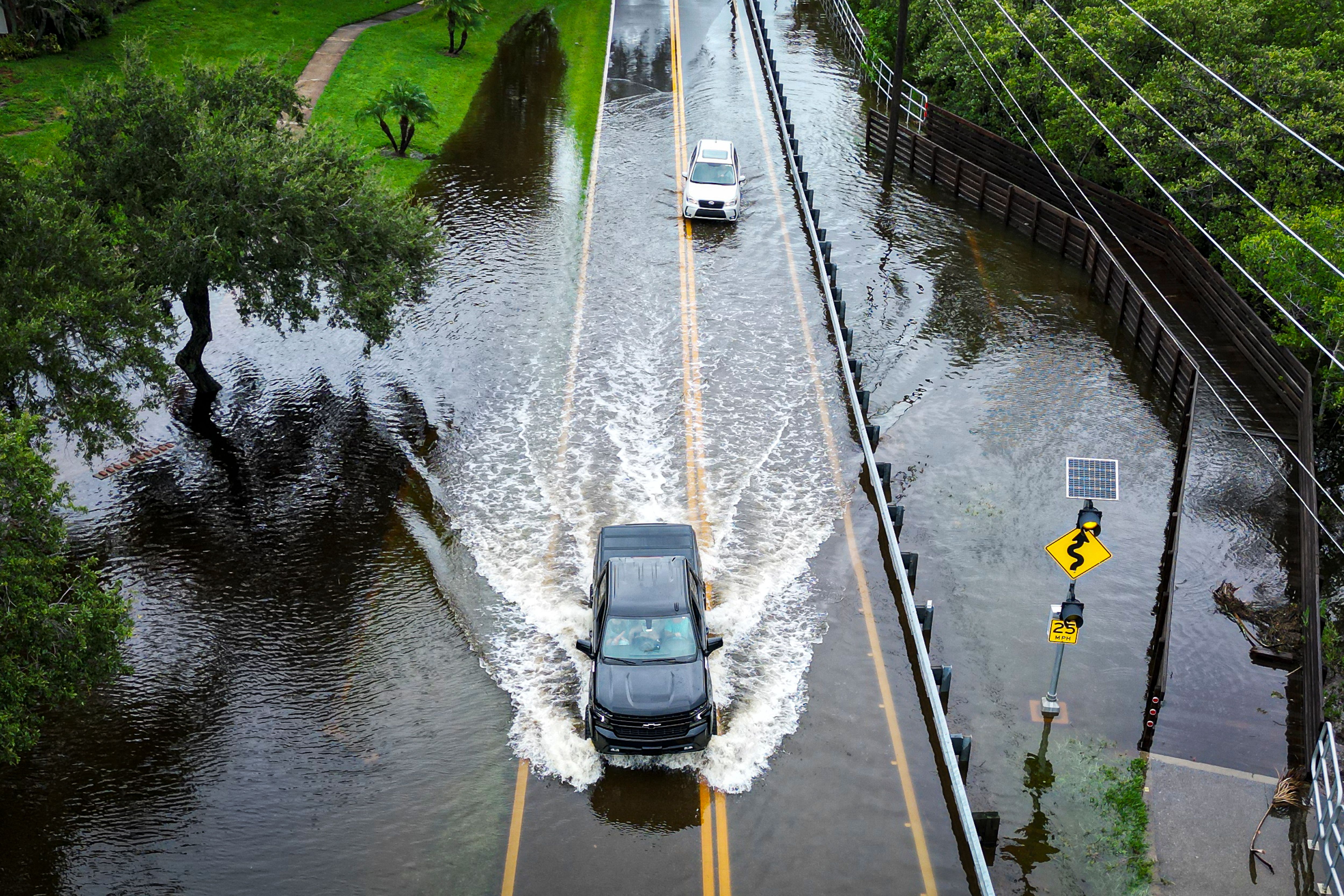 Cars attempt to drive on a flooded road in Tampa, Florida, Aug. 30, 2023, after Hurricane Idalia made landfall.