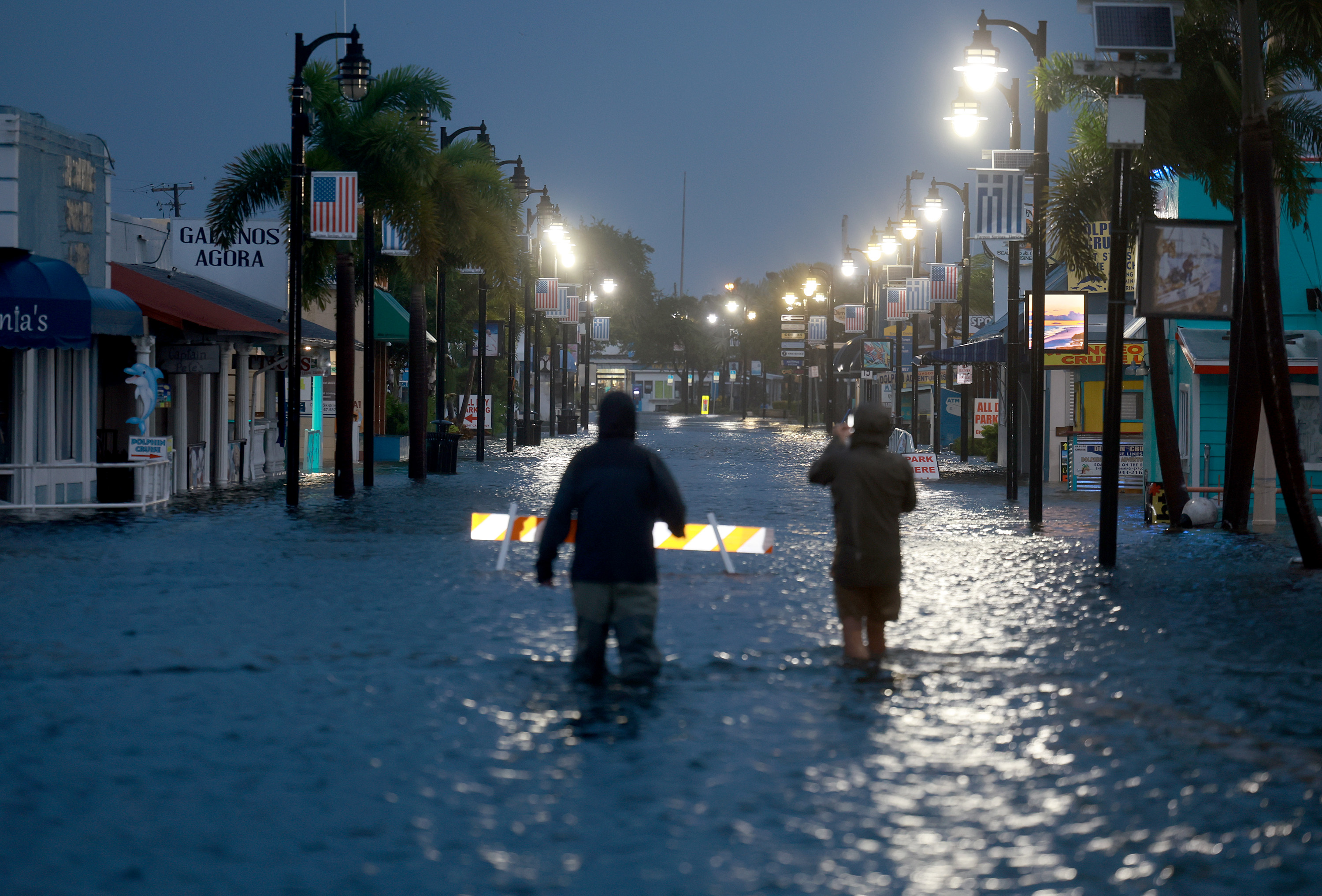 Reporters wade through flood waters as it inundates the downtown area after Hurricane Idalia passed offshore on Aug. 30, 2023, in Tarpon Springs, Florida.