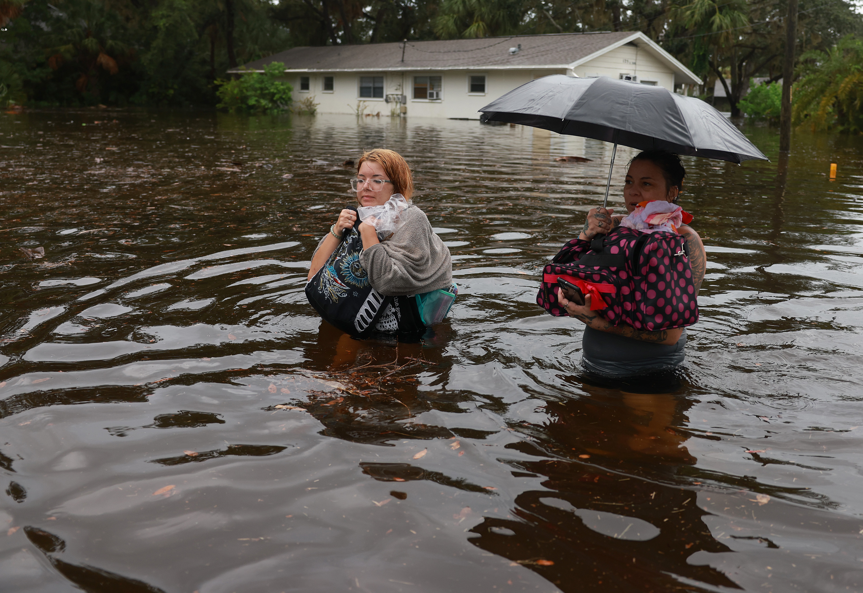 Makatla Ritchter, left, and her mother, Keiphra Line wade through flood waters after evacuating their home, Aug. 30, 2023, in Tarpon Springs, Florida.