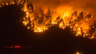 A wildfire frontline with emergency services nearby, Okanagan Valley, British Columbia, Canada