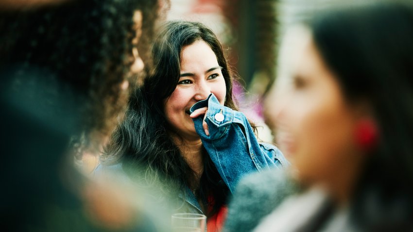 Laughing woman hanging out with friends during party at outdoor restaurant