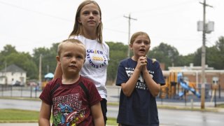 Hudson, 7, left, Callahan, 13, middle, and Keegan Pruente, 10, right, stand outside their school on their first Monday home during the new four-day school week on Monday, Sept. 11, 2023, in Independence, Mo.