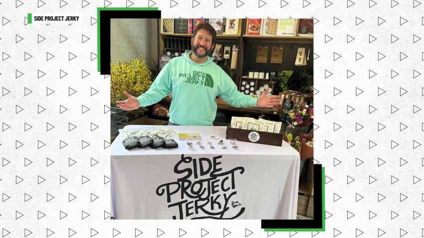 Man in hoodie stands behind booth for beef jerky business