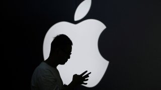 A man check his phone near an Apple logo outside its store in Shanghai, China September 13, 2023.