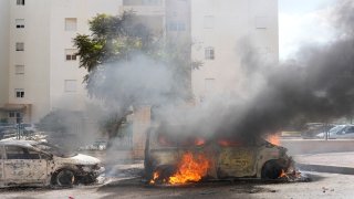 Cars are on fire after they were hit by rockets