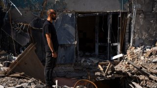 Dmytro Ihnatenko, owner of the destroyed Ria Pizza, stands beside a wide hole left from an Iskander missile that Russian forces used to strike a restaurant in June, killing 13 people and reducing the building to rubble, in  Kramatorsk, Ukraine, Wednesday, Sept. 13, 2023. Russia’s deadly attack on a beloved pizzeria in eastern Ukraine in June was painful for residents. The rubble remains in Kramatorsk as a reminder of the risk for businesses so close to the front lines. But many other shops and restaurants have defied the threat and reopened in recent months.