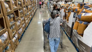 Shoppers look over blankets on sale in a Costco warehouse
