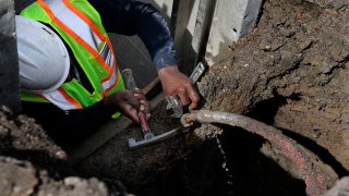 A man fixes and closes off a leaking lead service pipe