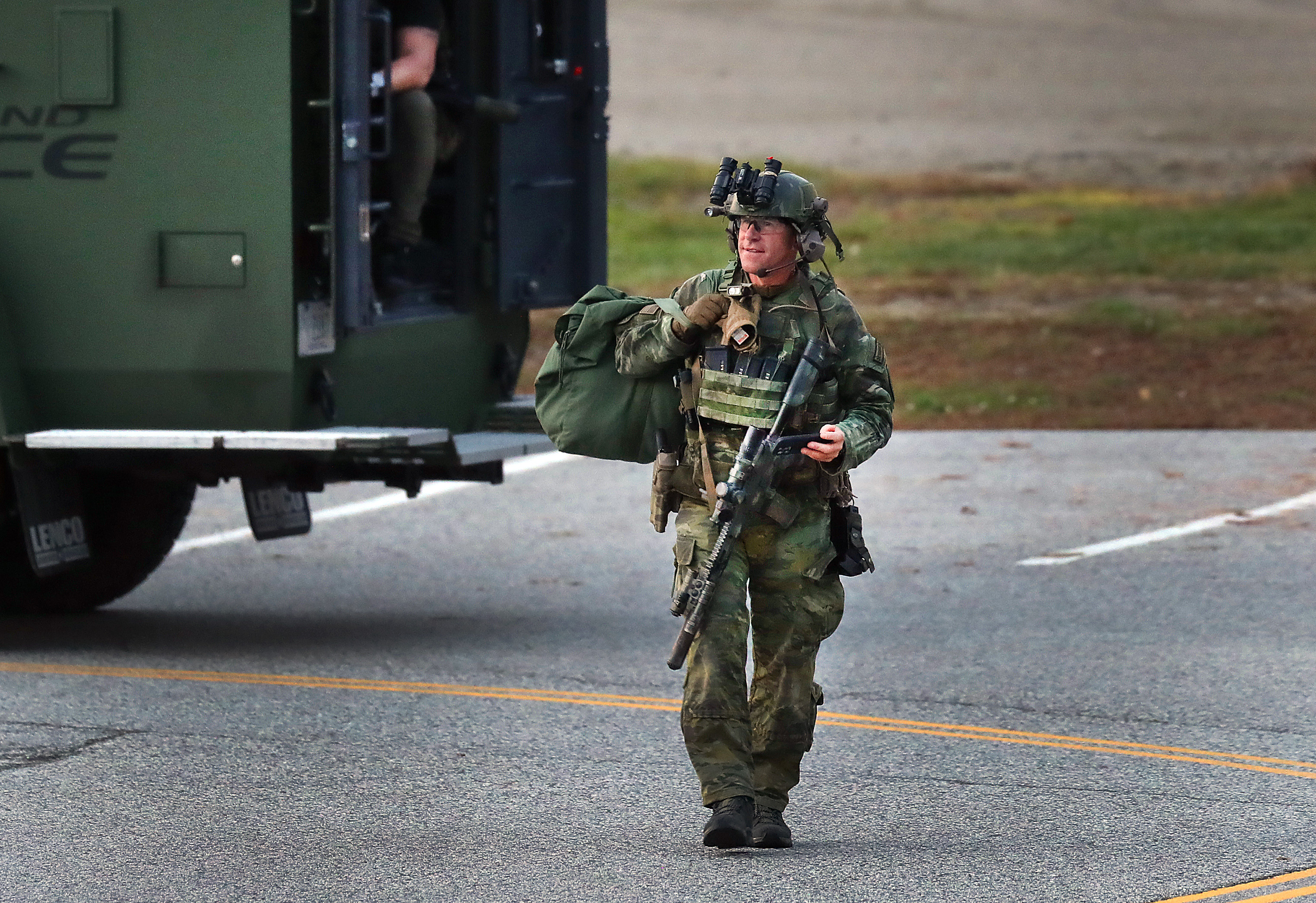 Heavily armed police boarded armored vehicles at Lisbon High School at daybreak as they search for the mass shooter, Oct. 26.