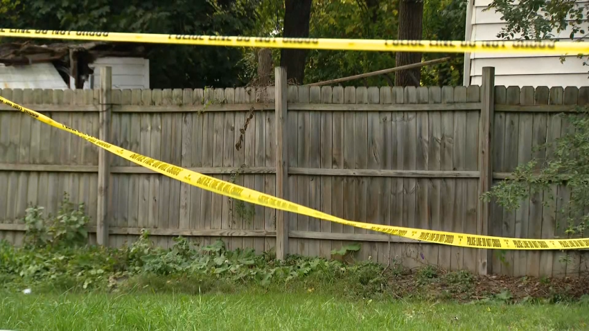 Police tape hangs along wooden fence