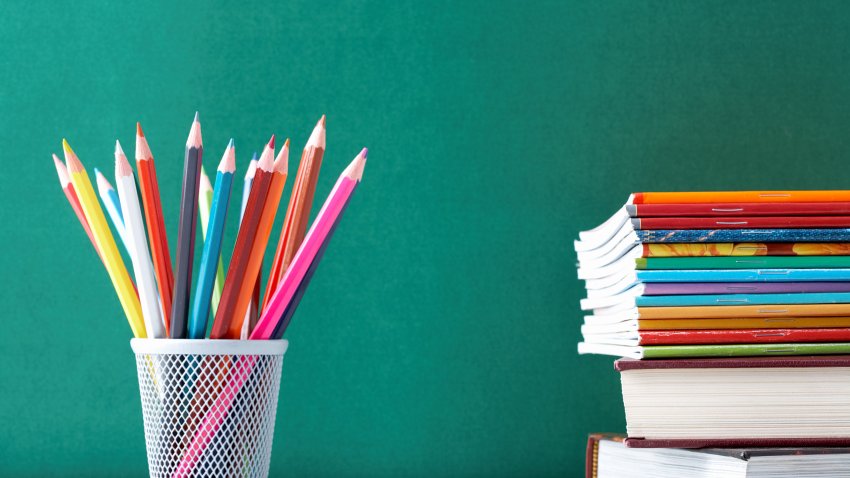 Image of crayons and exercise books against blackboard