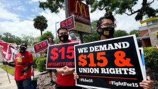 Workers hold signs in front of a McDonald's restaurant.