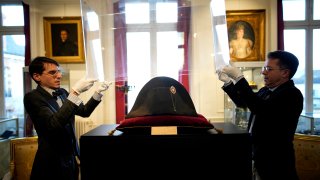 Raphael Pitchal, left, and Jean Christophe Chataignier of Osenat's auction house remove the protection of one of the signature broad, black hats that Napoléon wore