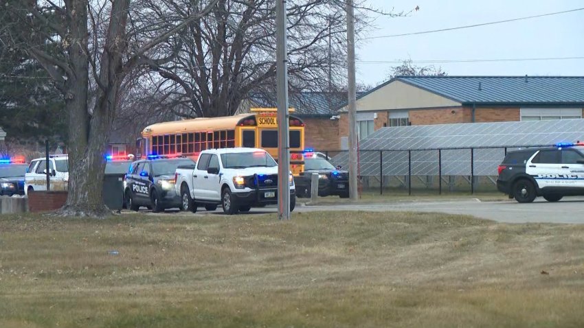 A bus drives by outside a high school with police activity