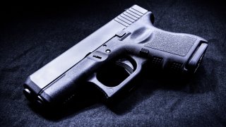 File. Handgun in a dark room lit by a single light source