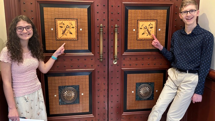 Sue Katherine Boye Williams, 16, a junior at the Watkinson School in Hartford, Conn. and Chris Tracy, 19, a senior at the school, stand near an inlaid design of Connecticut’s current State Insect, the European “Praying” Mantis, on the door to a hearing room at Connecticut’s Legislative Office Building in Hartford on March 8, 2024. Both testified before a legislative committee, urging lawmakers to replace the non-native praying mantis with the native Spring Azure Butterfly.