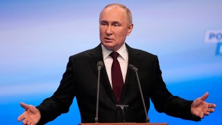 Russian President Vladimir Putin gestures while speaking on a visit to his campaign headquarters