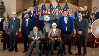 Ghost Army members John Christman, of Leesburg, N.J., second from left standing, Seymour Nussenbaum, of Monroe Township, N.J, in wheelchair at left, and Bernard Bluestein, of Hoffman Estates, Ill., in wheelchair at right, join military and congressional officials as members of their secretive WWII-era unit are presented with the Congressional Gold Medal during a ceremony on Capitol Hill, Thursday, March 21, 2024, in Washington.