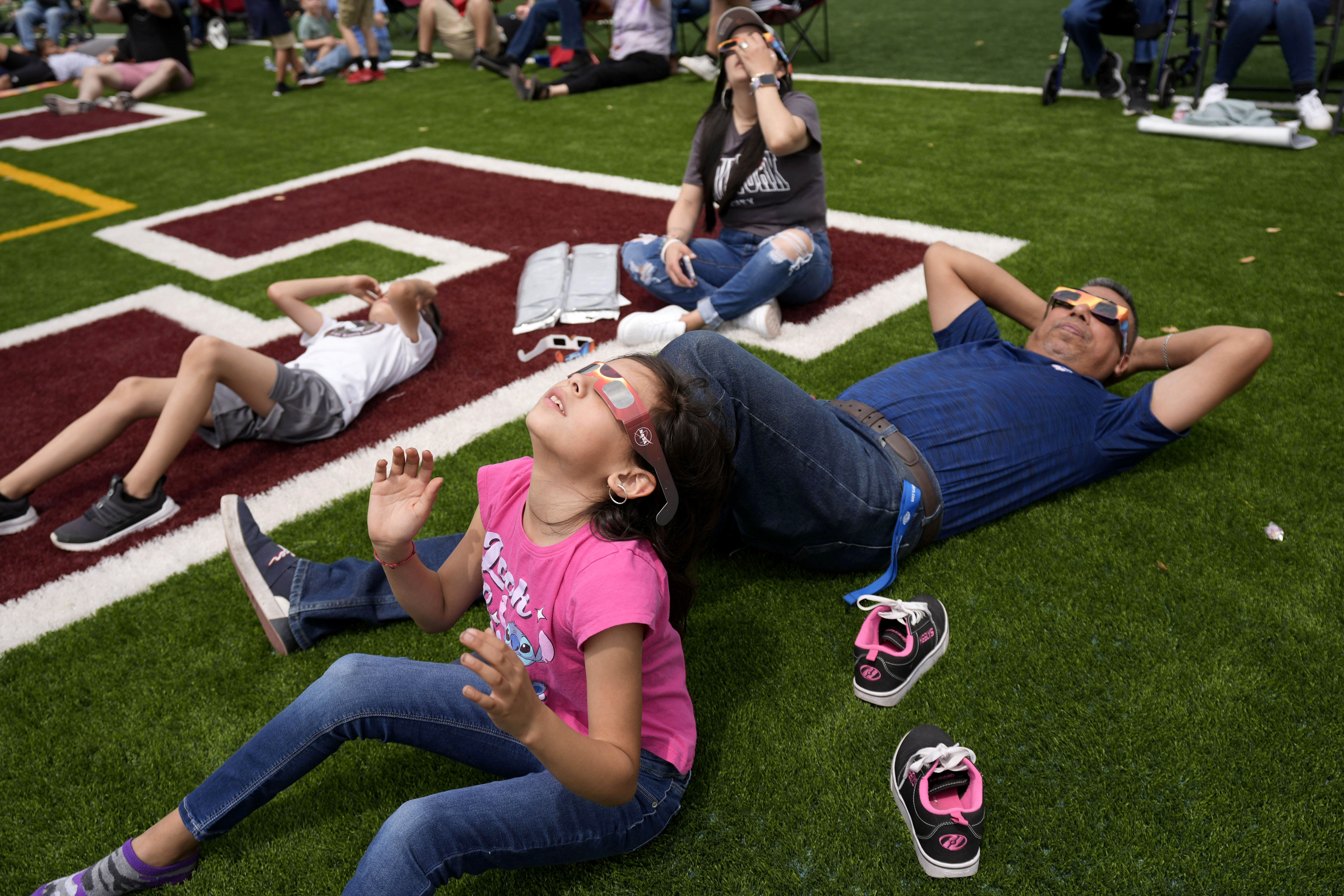 People watch as the moon partially covers the sun during a total solar eclipse, as seen from Eagle Pass, Texas, Monday, April 8, 2024.