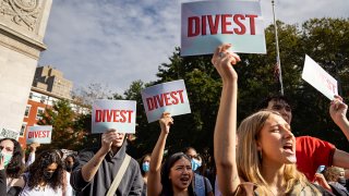 Students from New York University hold "Divest" signs while protesting the Israel-Hamas war, April 25, 2024.