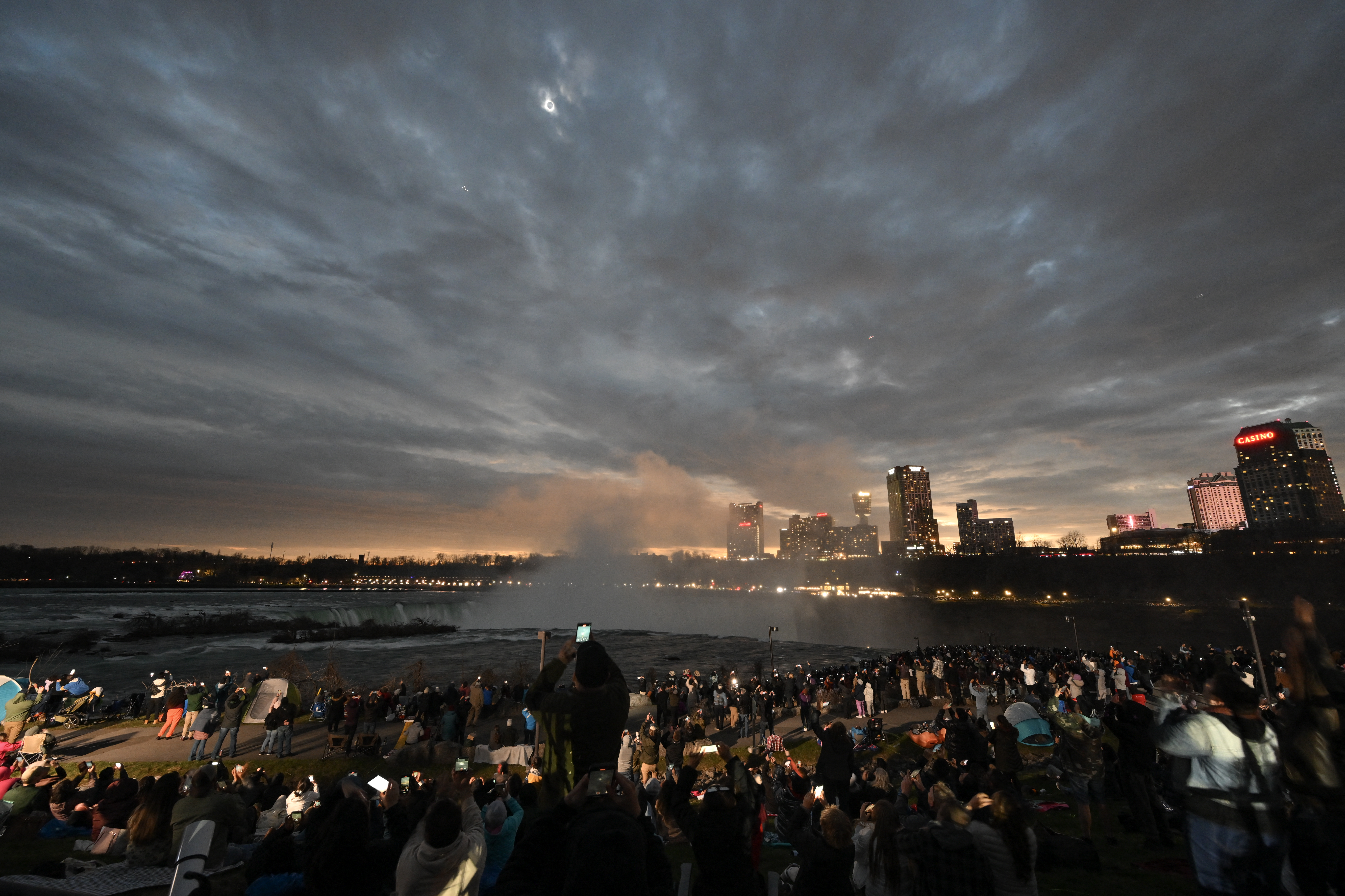 The sky darkens as people watch during totality of the total solar eclipse across North America, at Niagara Falls State Park in Niagara Falls, New York, on April 8, 2024.