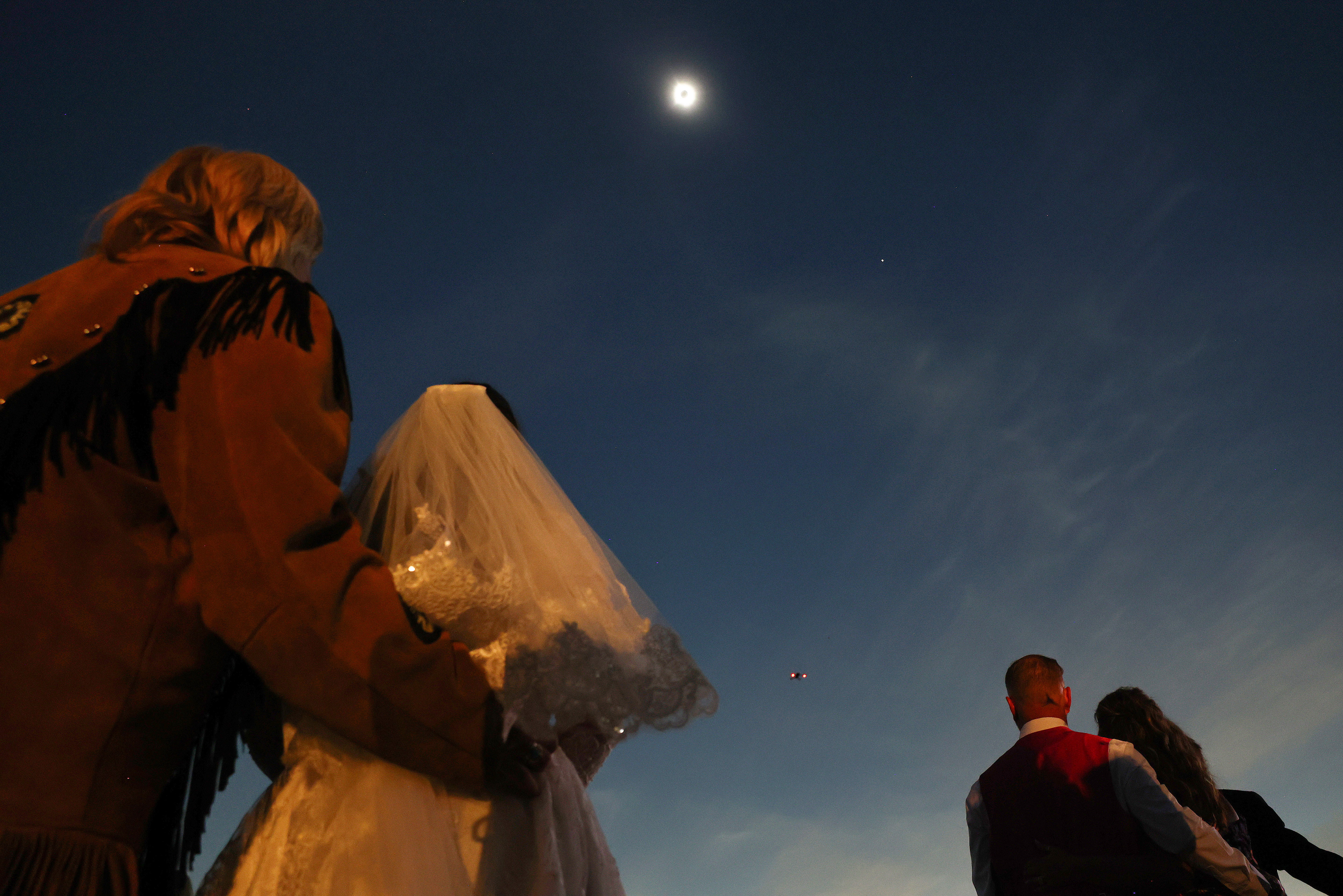 Couples view the solar eclipse during totality at a mass wedding at the Total Eclipse of the Heart festival on April 8, 2024 in Russellville, Arkansas.