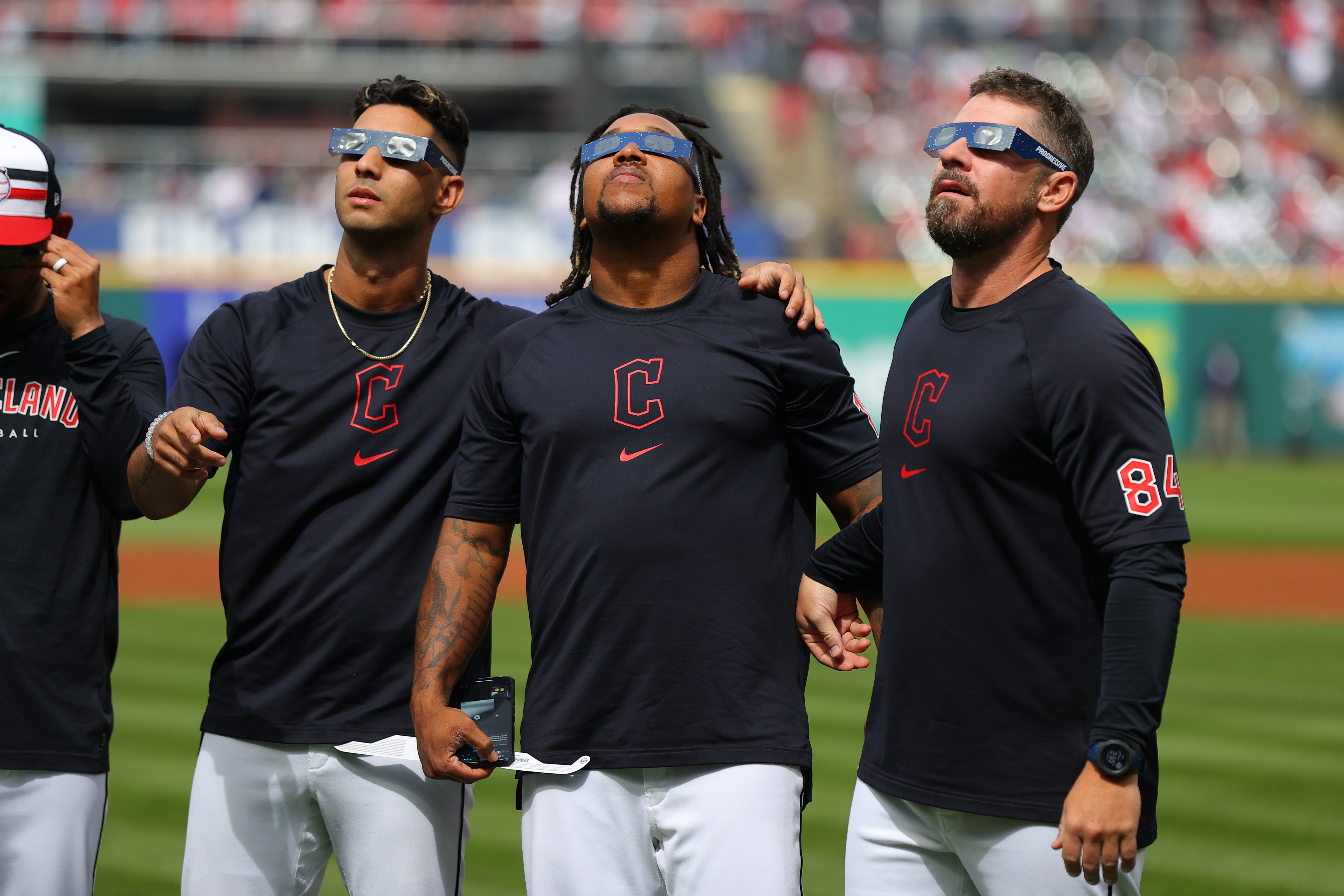 Brayan Rocchio #4, José Ramírez #11 and J.T. Maguire #84 of the Cleveland Guardians look up at the total solar eclipse before the home opener against the Chicago White Sox at Progressive Field on April 08, 2024 in Cleveland, Ohio. Cleveland is in the “path of totality” for today’s total solar eclipse.