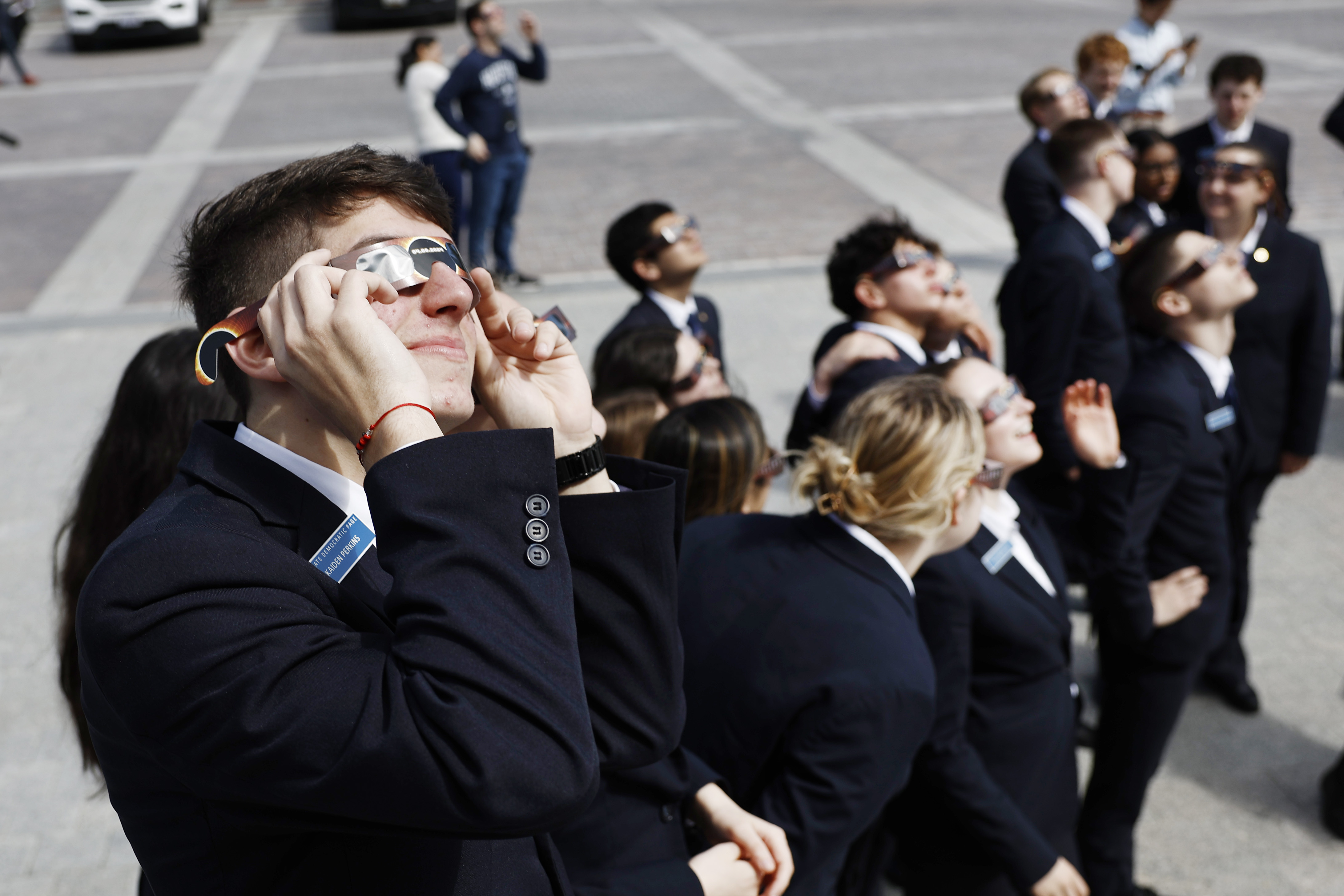 U.S. Senate Pages use eclipse viewing glasses to look up at the partial solar eclipse from the U.S. Capitol Building on April 08, 2024 in Washington, DC.