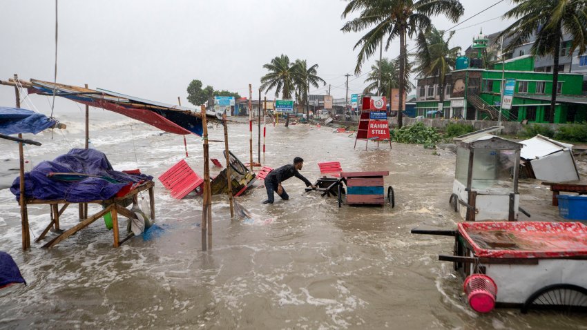 A man salvages a cart and other material as water flows on to the Kuakata beach on the coast of Bay of Bengal caused by the advancing Cyclone Remal in Barisal, Bangladesh, Sunday, May 26, 2024.