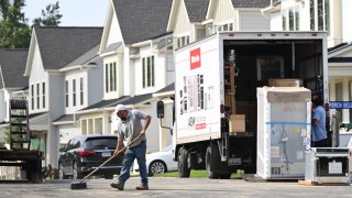 A maintenance worker sweeps the street in front of a row of new homes in Fairfax, Virginia, on August 22, 2023.