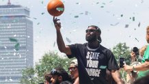 Jaylen Brown holds up a basketball atop a duck boat during the Boston Celtics' championship parade on Friday, June 21, 2024.