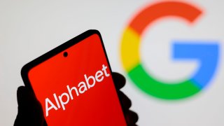 In this photo illustration, the Alphabet Inc. logo seen displayed on a smartphone screen and the Google logo in the background. 