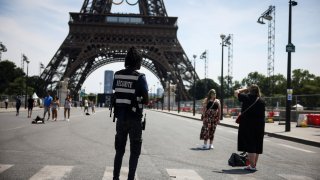 A security officer watches people taken photographs in front of the Eiffel Tower at the 2024 Summer Olympics, Saturday, July 20, 2024, in Paris, France.