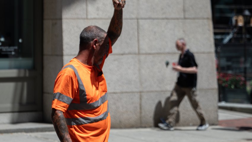 A construction worker wipes his brow while working on a hot day.